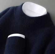 A dark blue knitted round-neck jumper with long sleeves, a ribbed hem and cuffs.