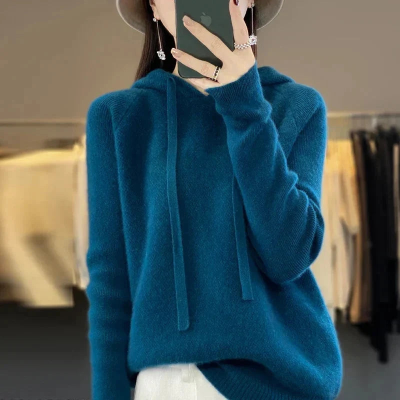 A petrol blue women's knitted hoodie with a drawstring hood.