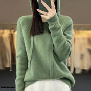 A light green women's knitted hoodie with a drawstring hood.
