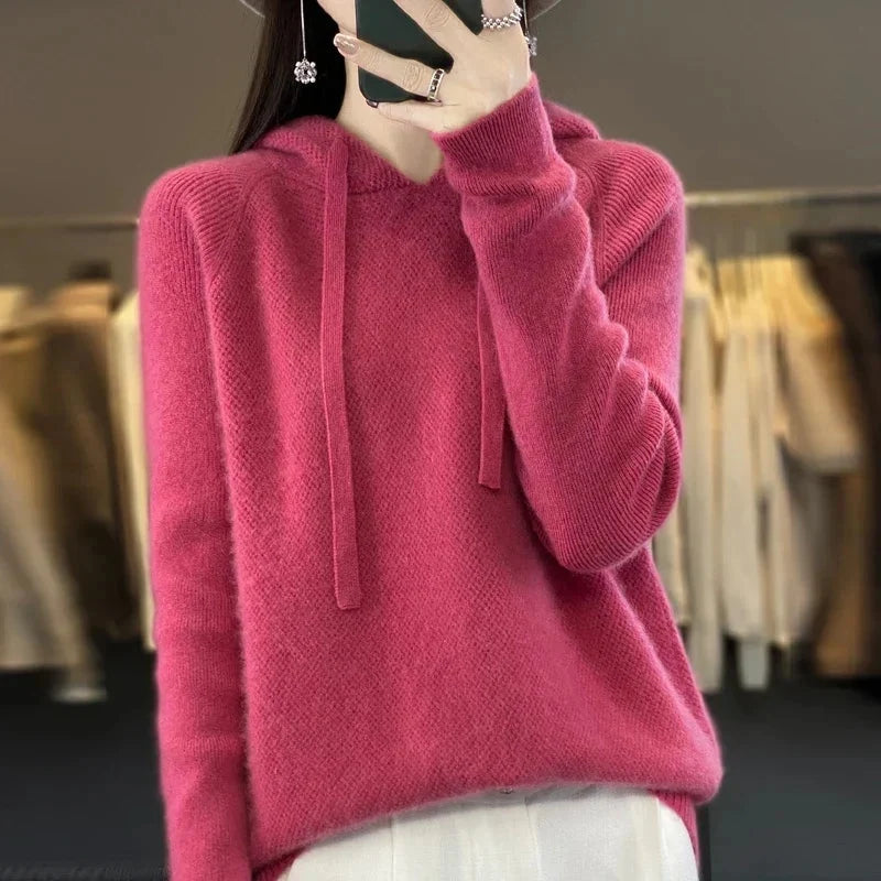 A pink women's knitted hoodie with a drawstring hood.