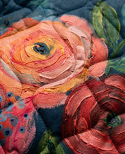 Gewatteerde damesjas met bloemenprint, donkerblauwe stof en kleurrijke roosmotieven.