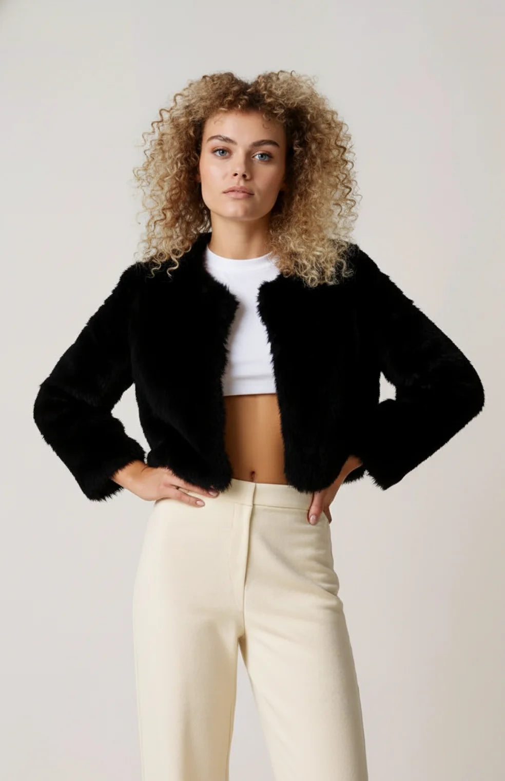 A cropped black women's furry jacket with an open front and long sleeves