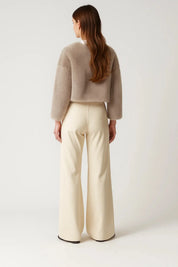 A cropped beige women's furry jacket with an open front and long sleeves