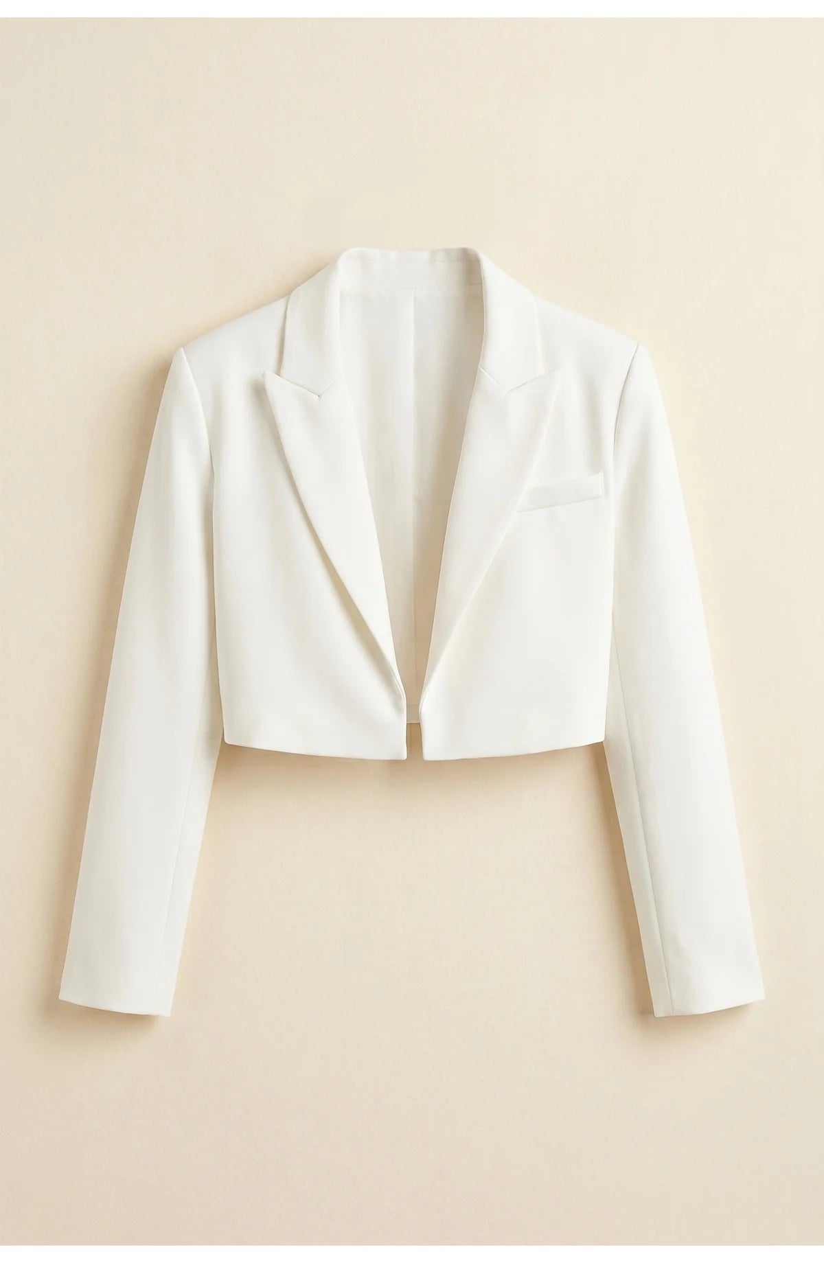 A cropped white blazer with long sleeves, a back yoke and straight hem, rear view