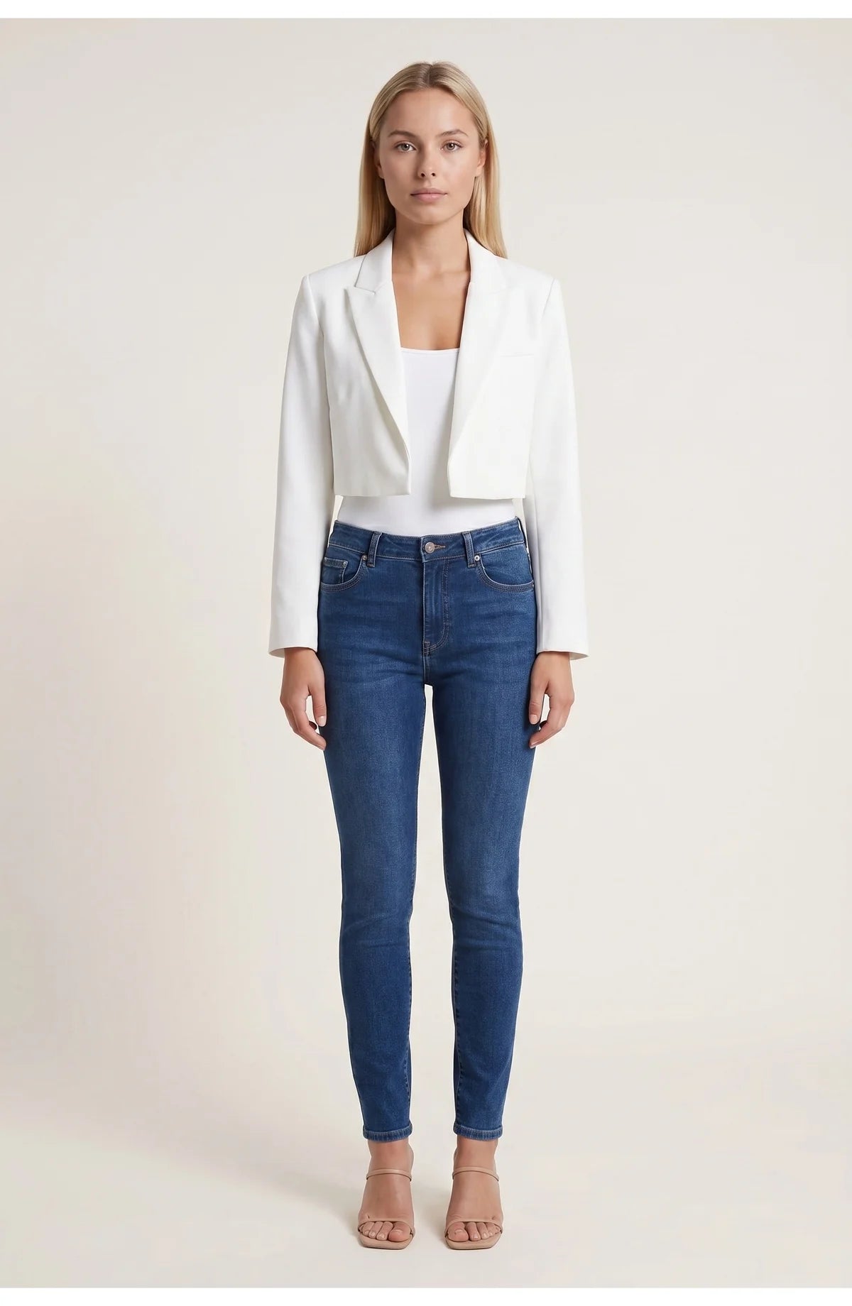 A cropped white blazer with long sleeves and lapels, worn with blue jeans