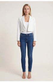 A cropped white blazer with long sleeves and lapels, worn with blue jeans
