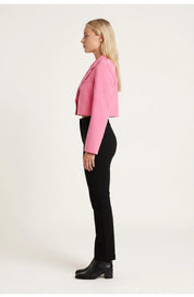 A cropped pink blazer with long sleeves and a lapel collar, side view