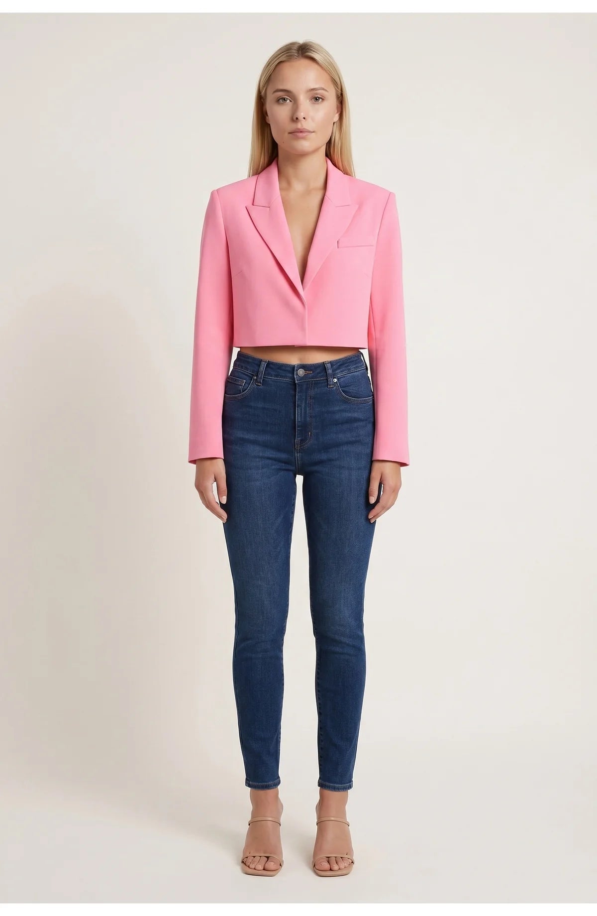 A cropped pink blazer with long sleeves and lapels, worn with blue jeans
