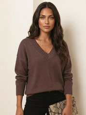 A loose-fitting brown knitted V-neck jumper with long sleeves and ribbed cuffs