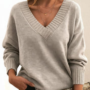 A loose-fitting cream women's knitted V-neck jumper with long sleeves and ribbed trims