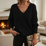 A loose-fitting black knitted V-neck jumper with long sleeves.