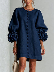 Donkerblauwe tuniekjurk met ballonmouwen en grote roosdetails, ronde hals en knooprij.