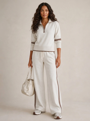 A light grey women's two-piece sports set with a zip-up jumper and wide-leg trousers with piping