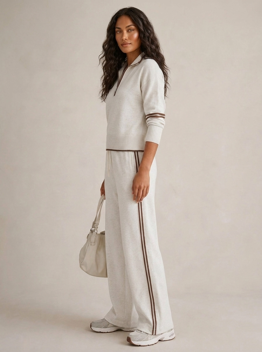 A light grey women's two-piece sports set with a zip-up jumper and wide-leg trousers with side stripes