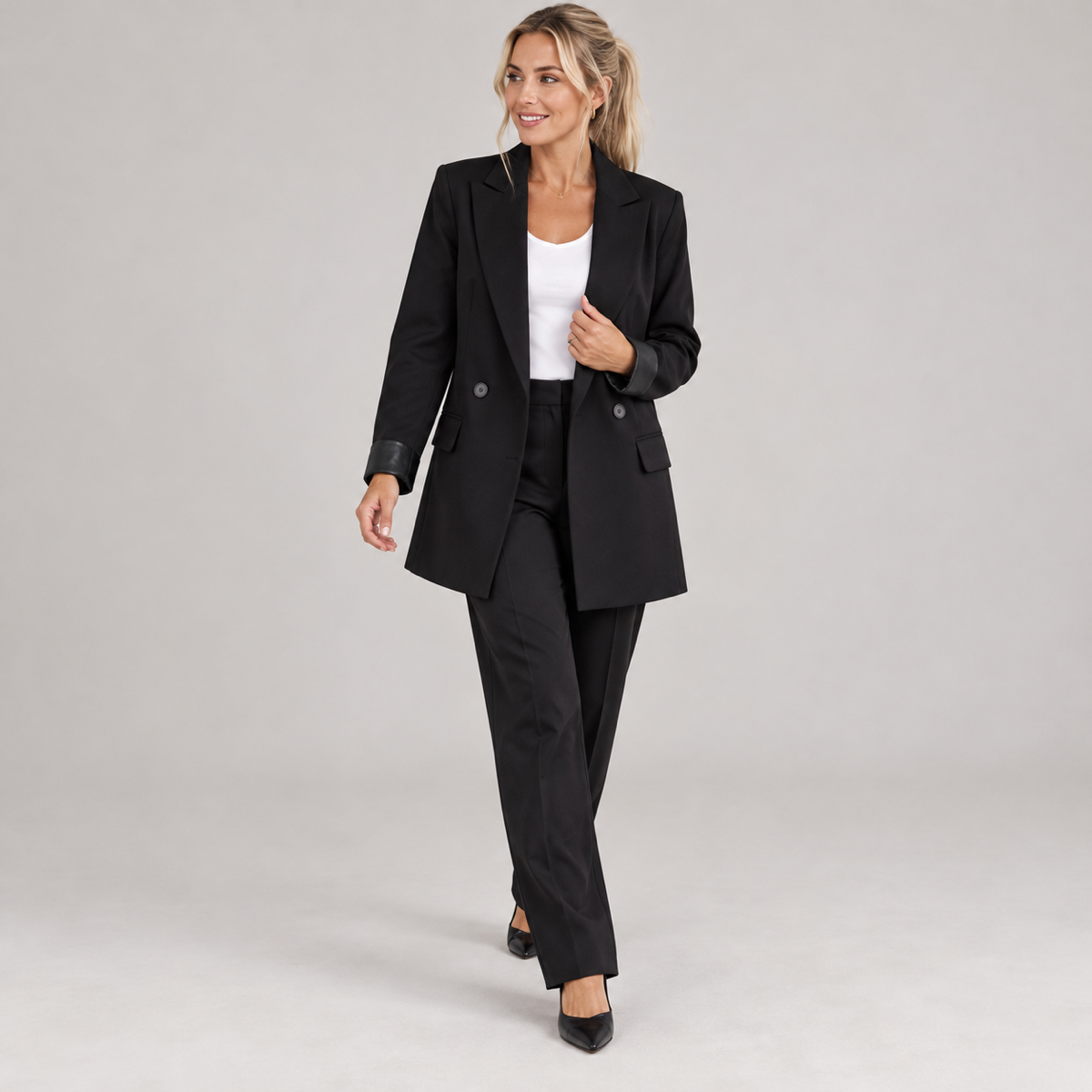 Women's black long oversized double-breasted blazer, worn by a female model in a walking pose