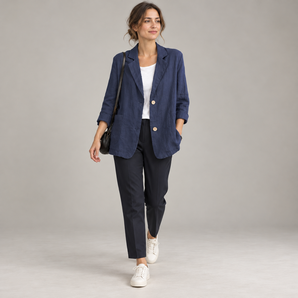 Women's loose-fit blazer with two buttons and roll-up sleeves, worn by a female model in a walking pose