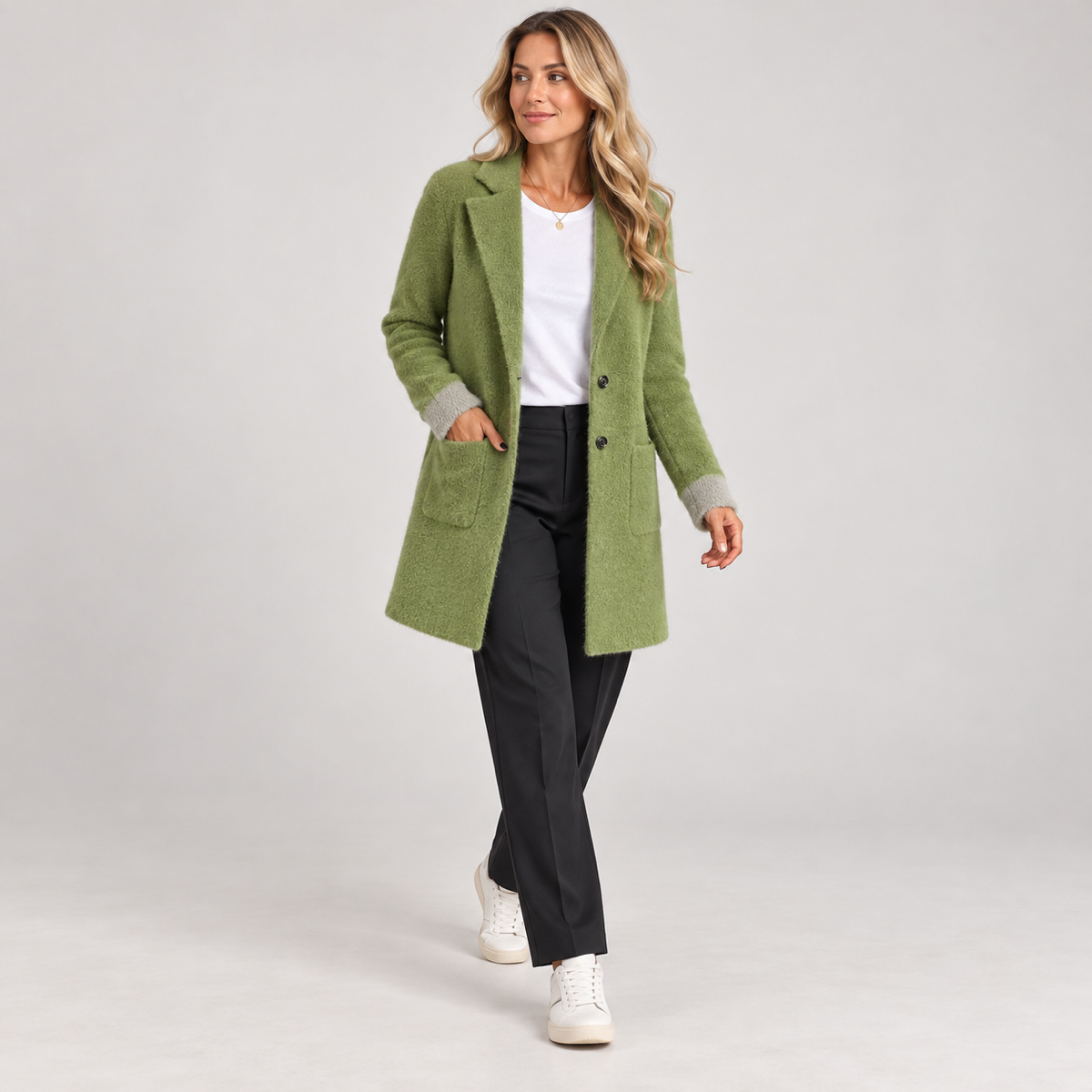 Women's long green oversized blazer with pockets, worn by a female model in a walking pose