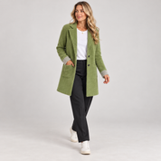 Women's long green oversized blazer with pockets, worn by a female model in a walking pose