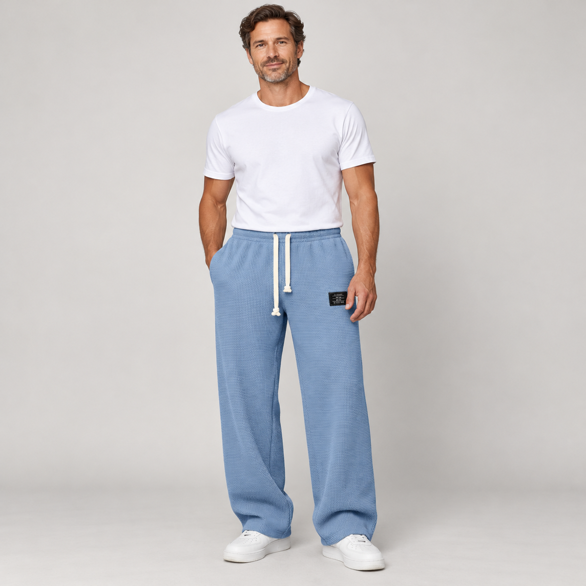 Men's wide-leg trousers with a drawstring and deep pockets, worn by a male model, close-up