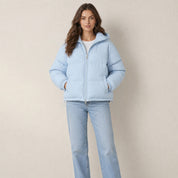 Model in babyblauwe korte pufferjas met capuchon, hoge kraag en zakken, vooraanzicht