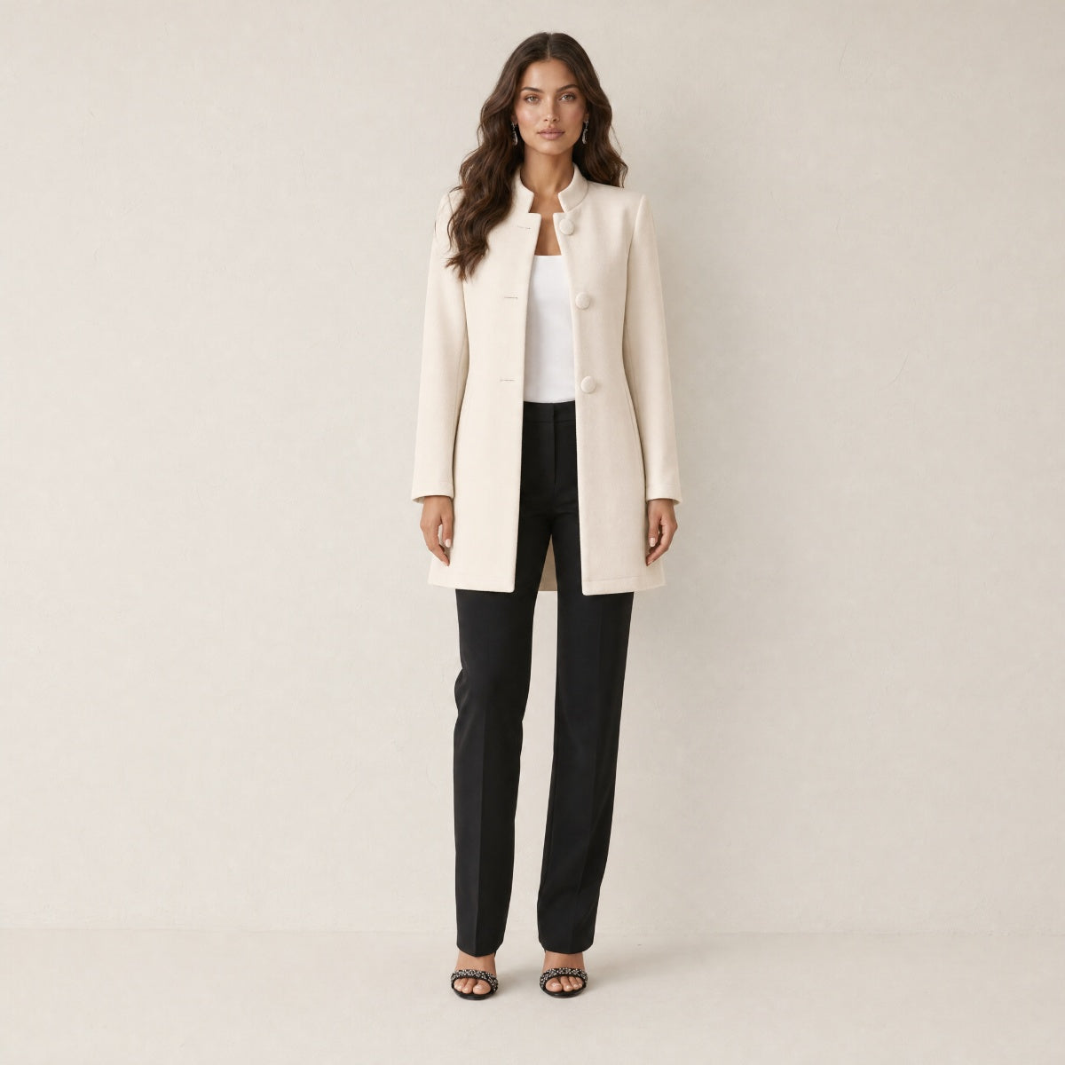 A model wearing a long cream women's collarless blazer, front view