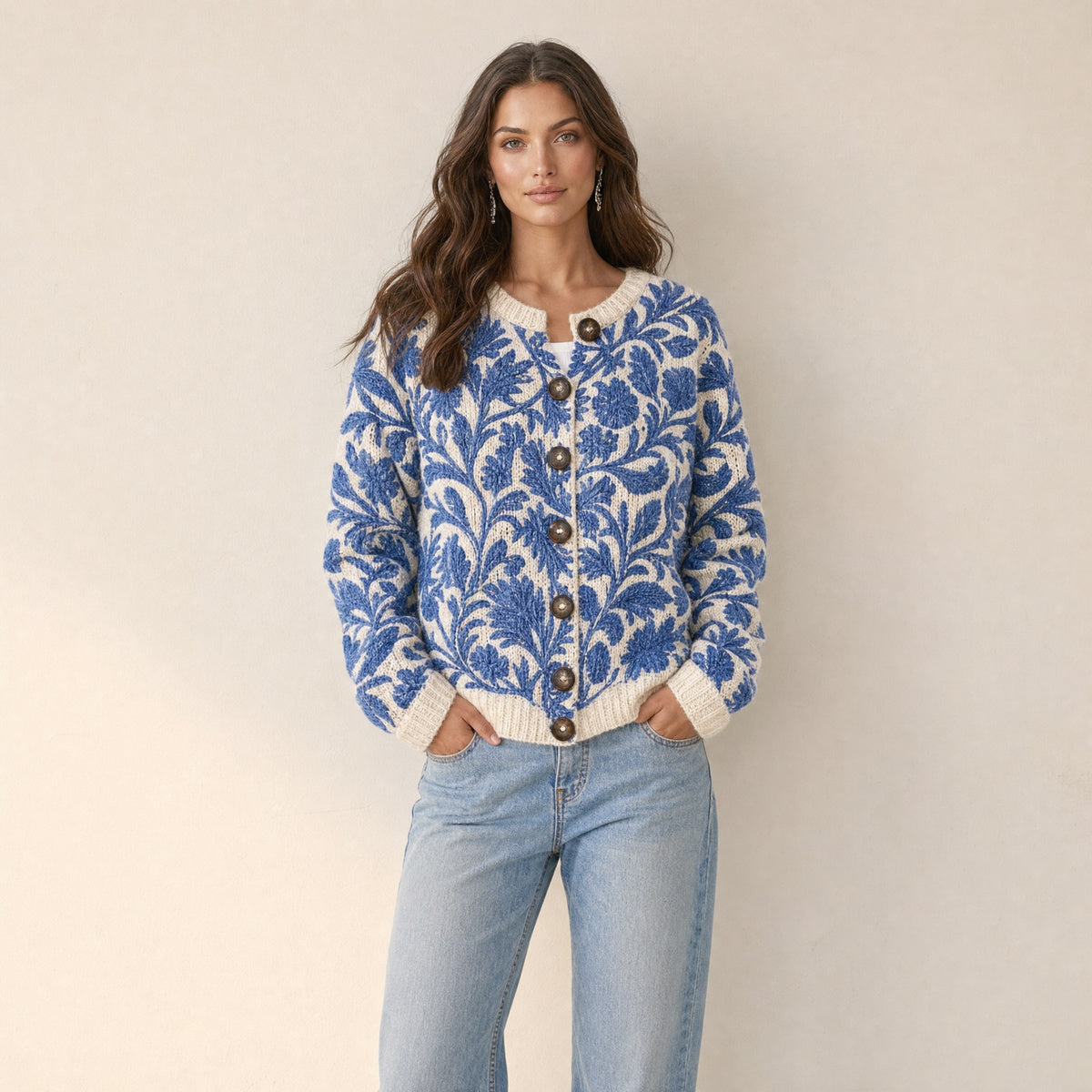 Model in ecru gebreid damesvest met blauwe bladprint en bruine knopen, vooraanzicht