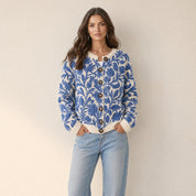 Model in ecru gebreid damesvest met blauwe bladprint en bruine knopen, vooraanzicht