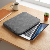 A dark grey faux leather laptop sleeve on a desk