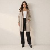 Model in lange beige winterjas met capuchon en teddyvoering, vooraanzicht