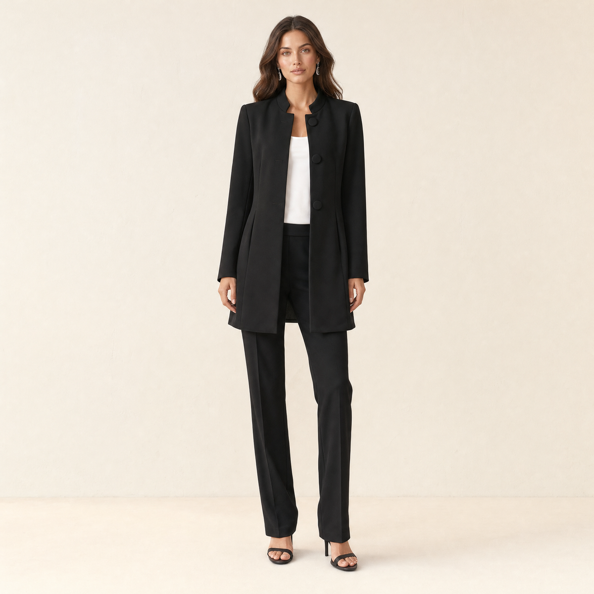 A model wearing a long black women's collarless blazer, front view