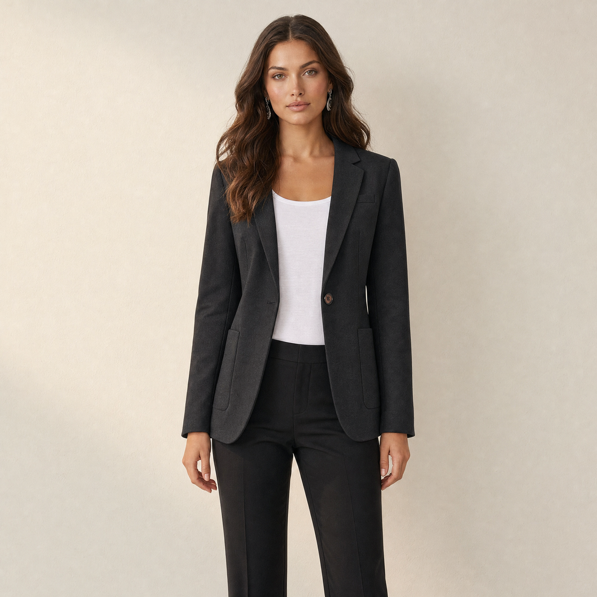 A model wearing a tailored black women's blazer with one button, front view